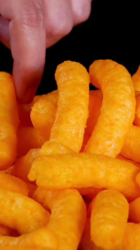 Hand Picking Up Crispy Cheese Puffs Against Black Background Stock Footage 322580355