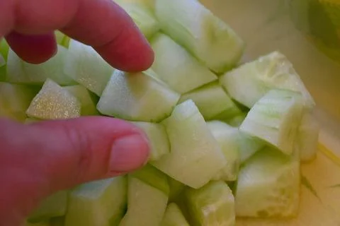 Hand picking cucumber cube close-up Stock Photos