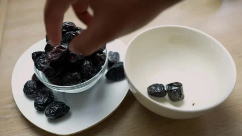 Hand picking dates from a bowl, with another empty bowl beside it Stock Footage 318125118