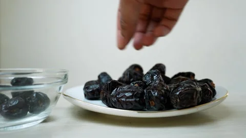 Hand picking dates from a plate next to a bowl Stock Footage 320726624