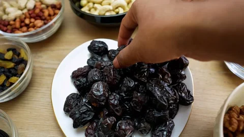 Hand Picking Dates from a Plate with Nuts and Fruits Stock Footage 318125057