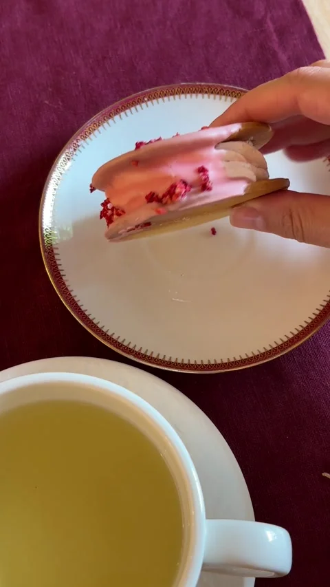A hand picking up a delicate pink glazed cookie sandwich Stock Footage 338005590
