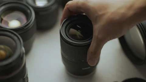 A hand picking down the lens of the camera between another lens. tools of trade  Video stock 128406106