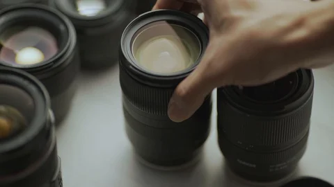 A hand picking down the lens of the camera between another lens. Video stock 128407541