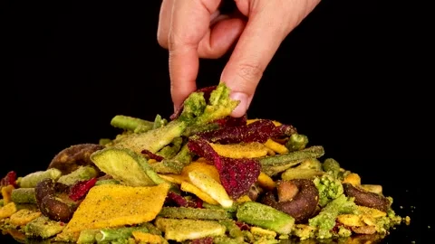 Hand Picking Dried Vegetable Chips from Colorful Snack Pile Stock Footage 319614929