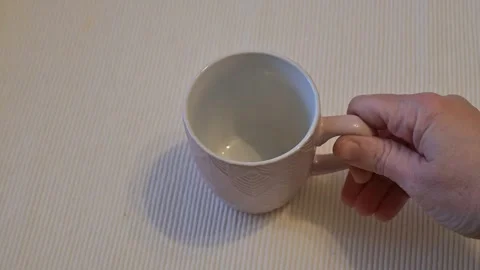 Hand picking up empty mug from table, coffee or kitchen lifestyle, Copy Space Stock Footage 334993091