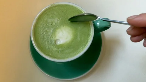 Hand picking foam from matcha latte Stock Footage 125466477