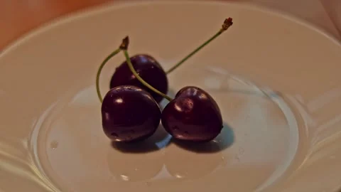 Hand picking up fresh cherry from white plate, macro close up Vidéo 346304158