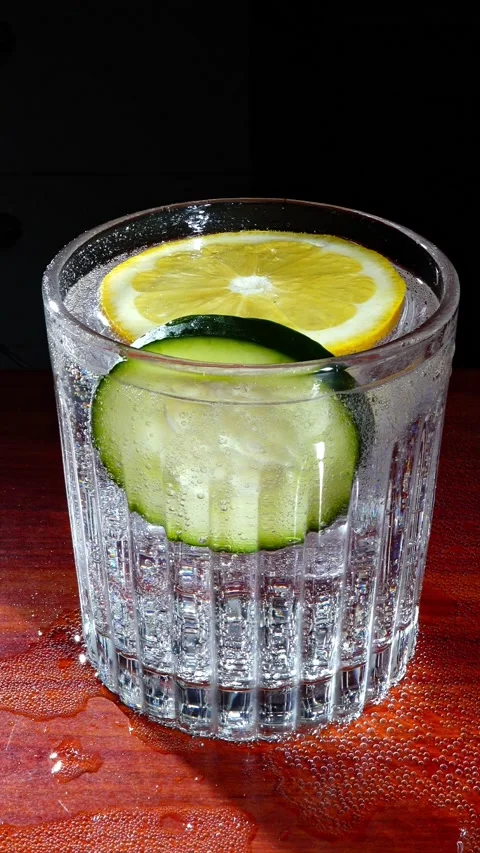 Hand Picking Up Fresh Gin Tonic Glass with Cucumber and Lemon Vertical Stock Footage 324598288