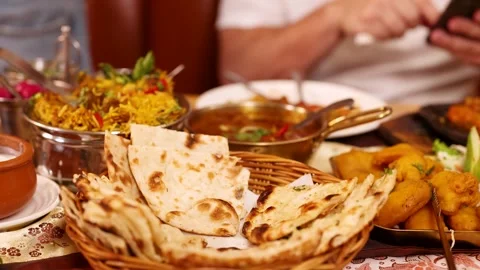 Hand Picking Up Fresh Naan Bread From Indian Food Spread Stock Footage 340374586