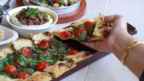 Hand Picking Freshly Baked Flatbread Pizza with Cherry Tomatoes and Basil. Stock Footage 315147526