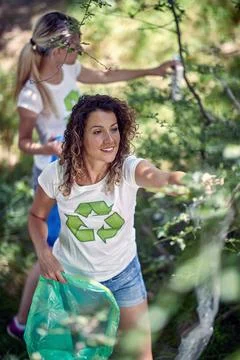 Hand picking up garbage and plastic for cleaning park or forest. Women in w.. Stock Photos