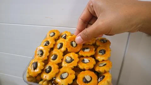 Hand picking glazed flower shaped cookies topped with dark chocolate and al.. Foto stock