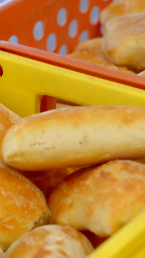 Hand picking golden rolls from yellow and orange bakery baskets in close, with 库存影片 344573314
