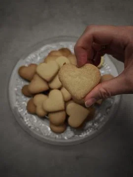Hand picking up heart shaped cookie from plate for valentine's day Stock Photos
