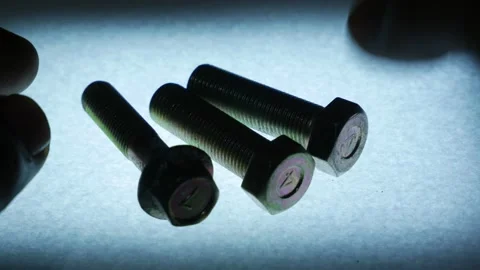 Hand Picking Up Metal Bolts One by One from Textured Surface Stock Footage 340069608
