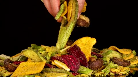 Hand Picking Mixed Dried Vegetable Chips Against Black Background Stock Footage 320594118