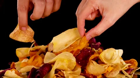 Hand Picking Mixed Root Vegetable Chips Against Black Background Stock Footage 320149791