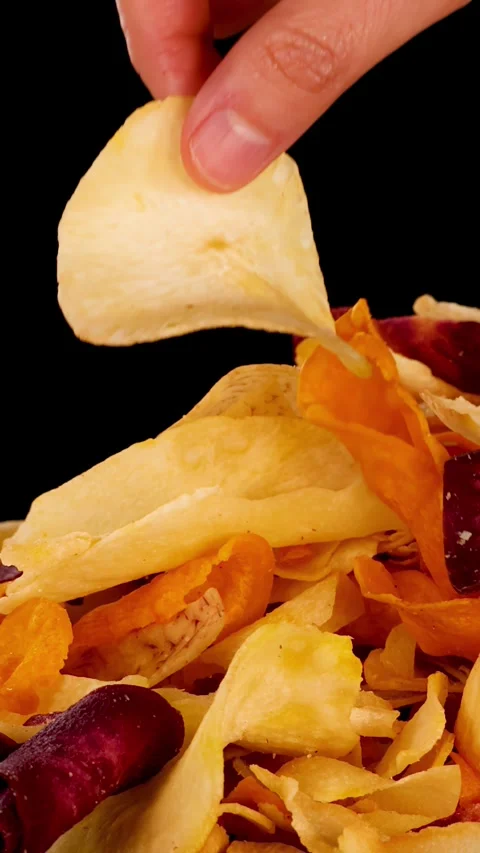 Hand Picking Mixed Root Vegetable Chips Against Black Background Stock Footage 323058998
