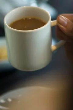 Hand picking up mug of coffee Stock Photos