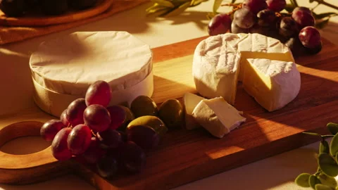 Hand picking an olive from a rustic wooden charcuterie board with whole and Stock Footage 334269617