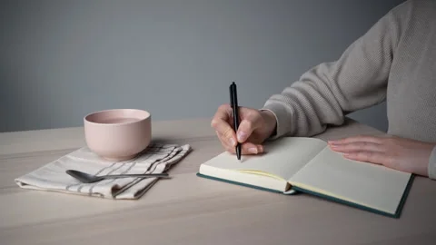 Hand Picking Up Pen to Continue Writing in Notebook Video stock 328003190