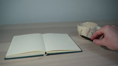 Hand picking up pen near notebook on table Video stock 327350145