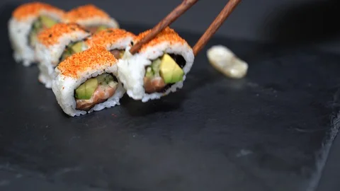 Hand picking up a piece of salmon roll with the chopsticks Stock Footage 129384217