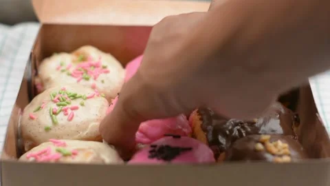 Hand Picking a Pink Sprinkled Donut from a Box Stock Footage 343519320