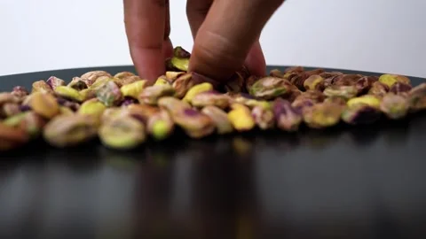 Hand Picking Pistachios from Black Surface Stock Footage 318057211
