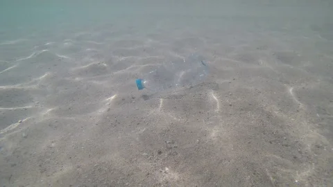 Hand picking up plastic bottle cleaning on the beach underwater Stock Footage 120179703