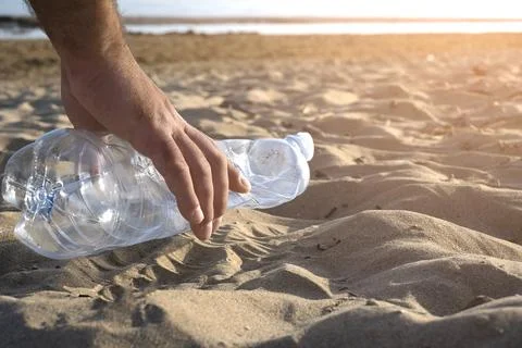 Hand picking up plastic bottle cleaning on the beach , volunteer concept Stock Photos