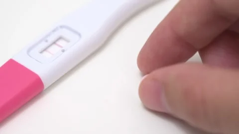 Hand Picking Up Prenatal Pill Next to Positive Pregnancy Test Stock Footage 340428356