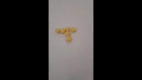 Hand Picking Puffed Golden Corn Cheese Ball From White Surface Stock Footage 337788284