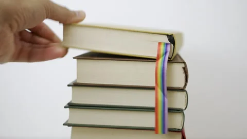 Hand picking up with rainbow flag books Vidéo 290463296