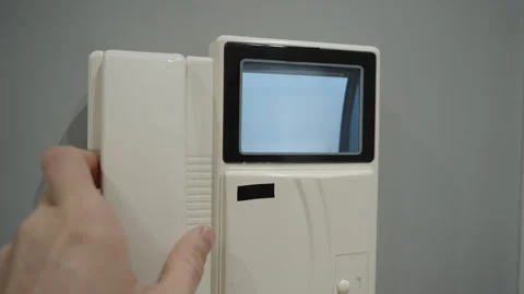 Hand Picking Up The Receiver Of An Old White Intercom With A Small Blue Screen Stock Footage 301352642