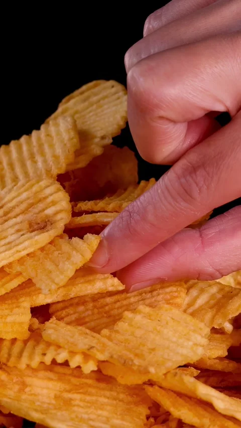 Hand Picking Ridged Potato Chips from Pile on Black Background Stock Footage 318645337