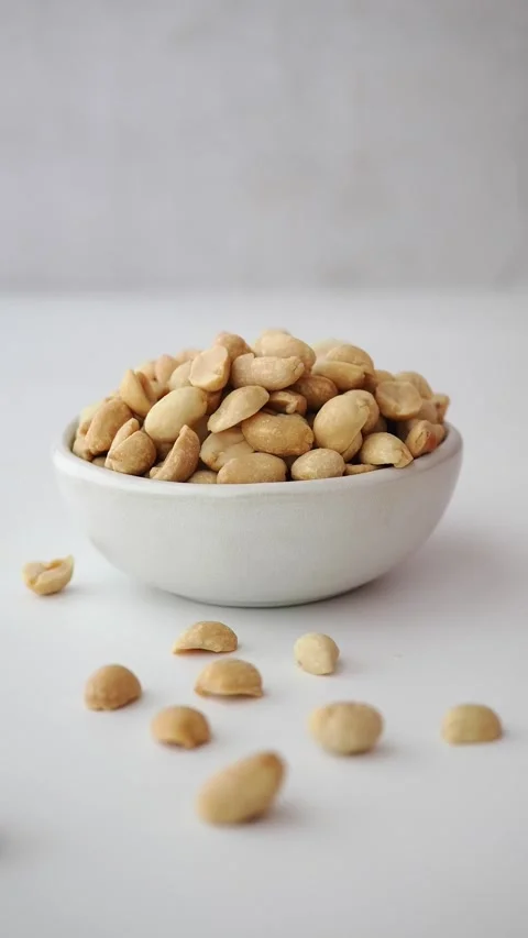 Hand Picking Roasted Peanuts from a Small Bowl Stock Footage 341221291