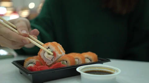 Hand picking up salmon sushi roll with chopsticks from tray  库存影片 337202179