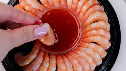 Hand picking shrimp from rotating seafood platter and dipping into sweet and Stock Footage 308003736