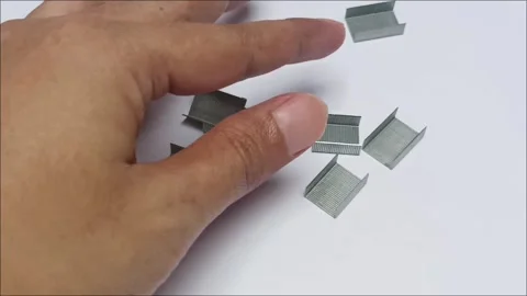 Hand picking silver metallic staple pins from table 스톡 동영상 338140789