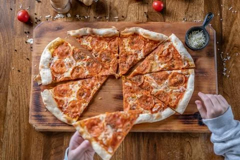 Hand picking slice hot pepperoni pizza Stock Photos