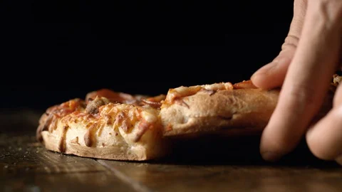 A hand picking up a slice of pizza out of a whole pizza. Slow Motion. Stock Footage 128973849