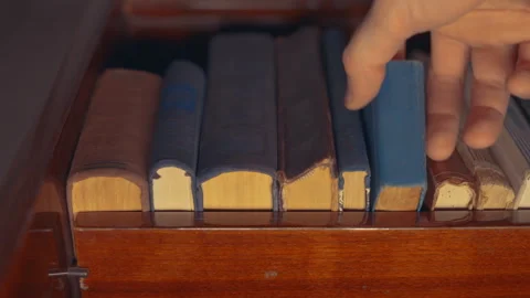 Hand Picking Small Antique Book from Wooden Shelf: Close-Up Bottom-Up Angle View Stock Footage 339110977