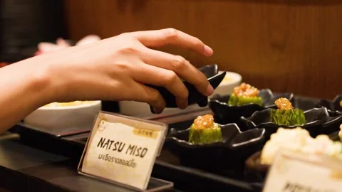 Hand Picking Small Appetizer Dish from Japanese Buffet Counter Stock Footage 341299349