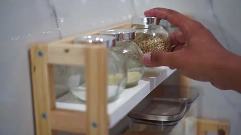 Hand picking up spice jar from kitchen shelf, cooking ingredient storage, Stock Footage 344011418