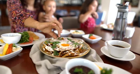 Hand picking tortilla chip with cheese and coriander from plate of chilaquiles Stock Footage 168642330