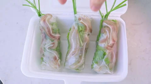 Hand picking vietnamese pork ear spring roll from takeaway container Stock Footage 337360382