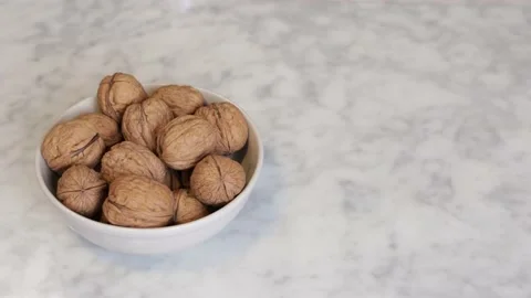 Hand picking up a walnut from a bowl Stock Footage 159952692