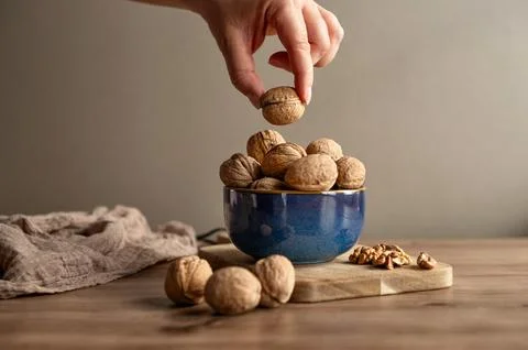 Hand picking walnut from rustic bowl Stock Photos